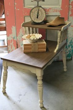 a table with books and a clock on it in front of a pink painted wall