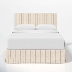 a bed with white sheets and pillows on it's headboard, in front of a wall