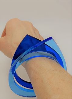 a person's hand with a blue ribbon around their wrist on a white surface