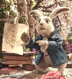 a white rabbit is standing in front of some books and looking at the camera while holding an open book