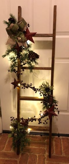 a ladder decorated with pine cones and greenery on the side of a door for christmas