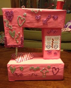 a pink toy sewing machine with sequins and hearts on it's sides