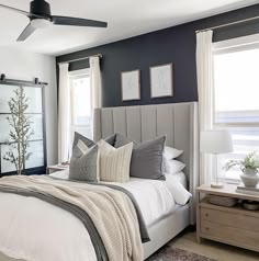 a bedroom with black walls, white bedding and gray accents is pictured in this image