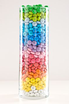 a glass filled with lots of different colored candies