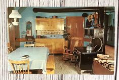 an old fashioned kitchen with blue walls and wooden furniture in the center, along with other antique appliances