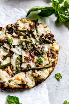 a pizza topped with cheese and asparagus on top of a piece of paper