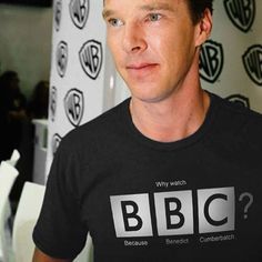 a man wearing a black t - shirt with the bbc logo on it is looking at the camera