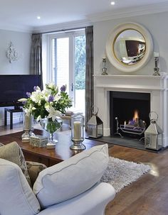 a living room filled with furniture and a fire place in front of a tv mounted on a wall