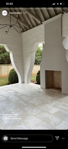 an outdoor fireplace in the middle of a room with white walls and tile flooring