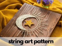 a wooden plaque with a star and moon on it, sitting on a yellow blanket