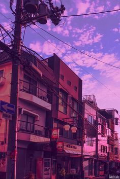 a city street filled with lots of traffic under a purple and blue sky covered in wispy clouds