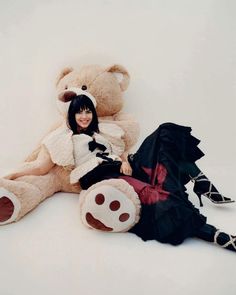 a woman sitting next to a giant teddy bear