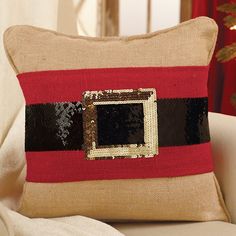 a red and black pillow sitting on top of a white couch next to a christmas tree