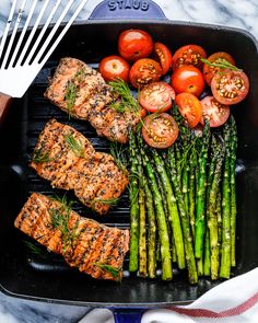 grilled salmon, asparagus and tomatoes on a grill pan with tongs