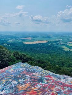 a view from the top of a hill with graffiti on it and trees in the background