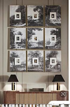 a living room with pictures hanging on the wall and two lamps in front of it