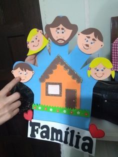 a person holding up a paper cut out of a house with family pictures on it