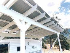 a white trailer parked under a pergolated roof