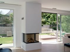 a modern fireplace in the middle of a living room with sliding glass doors leading outside