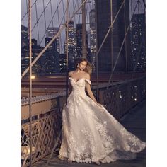 a woman in a wedding dress standing on a bridge with the city lights behind her