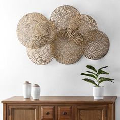 a wooden sideboard topped with two vases next to a wall mounted art piece