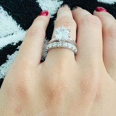 a woman's hand with two wedding rings on her left and the other hand holding an engagement ring