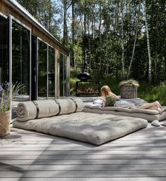 a woman laying on top of a large outdoor couch next to a forest filled with trees