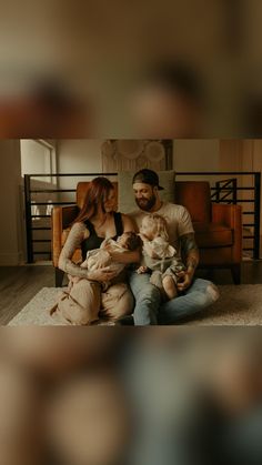 a man and woman are sitting on the floor with their two babys in front of them