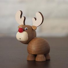 a wooden toy with a red nose and antlers on it's head sitting on a table