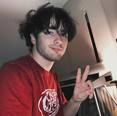 a young man making the peace sign with his fingers