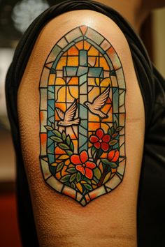 a stained glass window with two birds and flowers on the upper half of the arm