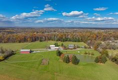 an aerial view of a farm with lots of grass and trees in the foreground