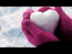 a person's hand holding a white heart in the middle of their mitts