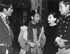 an old black and white photo of three men in uniform talking to two women wearing scarves