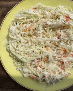 a yellow plate topped with coleslaw and carrots