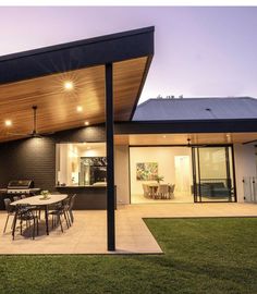 an outdoor dining area is lit up at night with lights on the ceiling and patio furniture