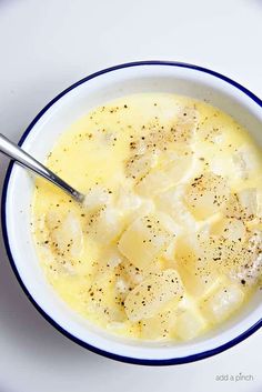 a white bowl filled with soup on top of a blue and white saucer next to a spoon