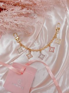 Elevate your accessories with our brand-new handbag charms, each delicately designed to compliment your designer handbags.  A mix of five Pastel Fleur Charms set on a gold link chain. Two gold snap hooks complete the piece.