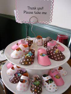 there is a three tiered tray with baby shoes on it