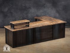 a large wooden counter sitting on top of a brown floor next to a black wall