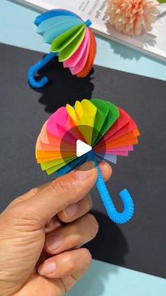 a hand holding a colorful paper umbrella