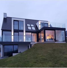 a modern house with large windows on top of the grass covered hill in front of it