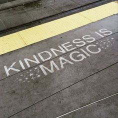 a sign that says kindness is magic written on the ground next to a train track