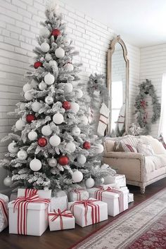 a white christmas tree with red and silver ornaments is surrounded by presents on the floor