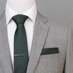 a man in a suit with a green tie and pocket square on his lapel