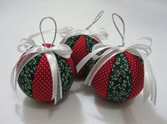 three red and green christmas balls with white ribbons on them sitting next to each other