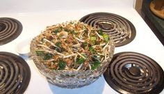 a glass bowl filled with food sitting on top of a white stovetop next to four burners