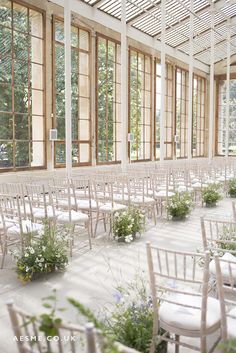 rows of white chairs with flowers in them and windows on the wall to the side