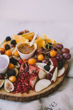 an assortment of fruits and dips on a wooden platter