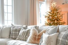 a living room filled with furniture and a christmas tree in the window sill behind it